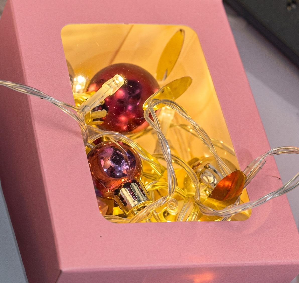 Kupferlichterkette mit roten Christbaumkugeln